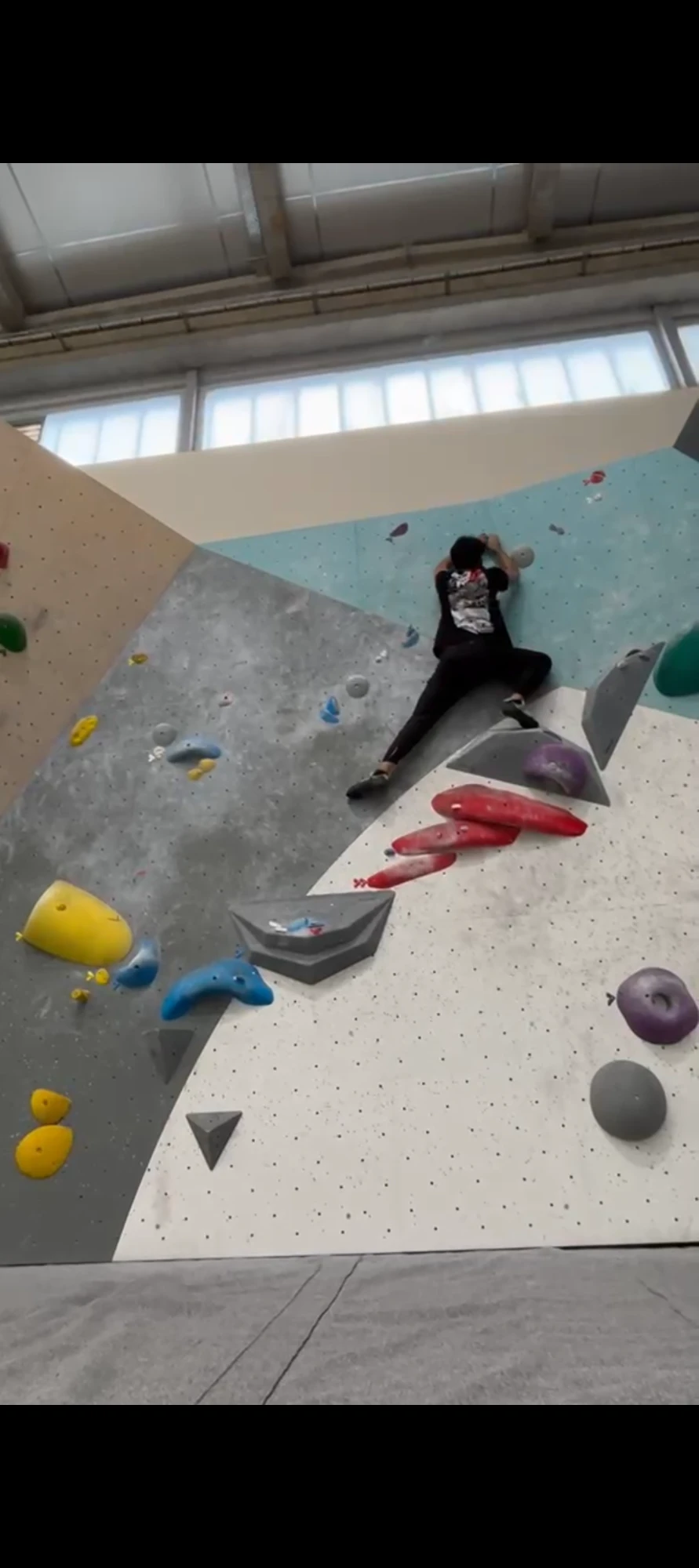 Ali Zaman escaladant un mur de bloc coloré en salle