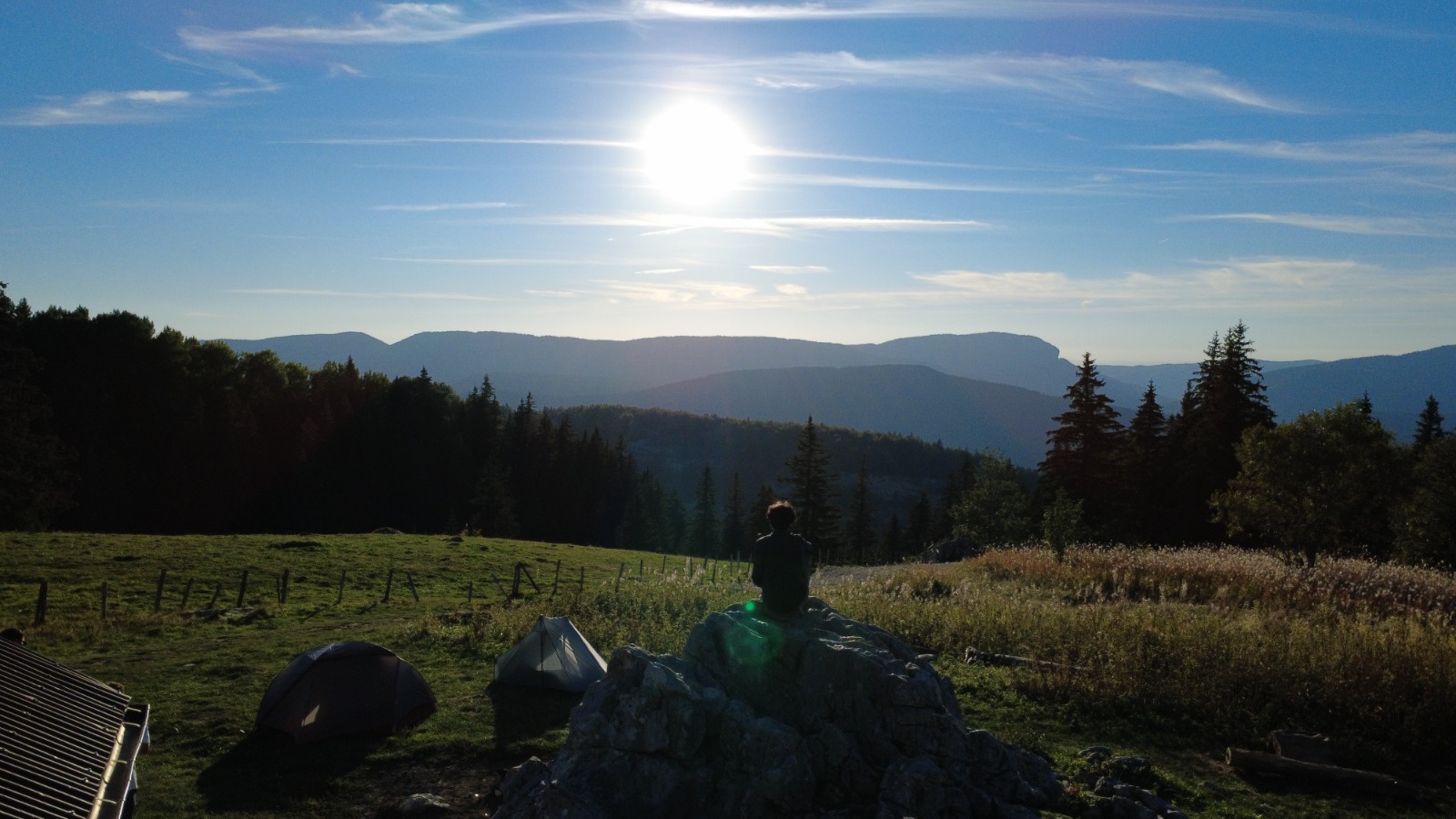 Ali Zaman assis sur un rocher face au coucher de soleil, lors d'un bivouac