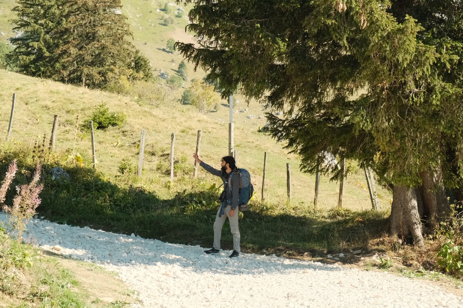 Ali Zaman en randonnée sur un chemin de montagne, le long d'une clôture